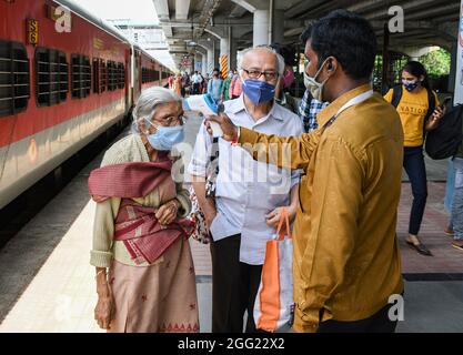 Mumbai, Indien. August 2021. Ein Mitarbeiter des Gesundheitswesens überprüft die Temperatur einer Frau am Dadar Terminus.Passagiere, die mit dem Außenbahnhof ankommen, müssen sich einer Temperaturkontrolle und in einigen Fällen einem RT-PCR-Test unterziehen, bevor sie zu ihrem jeweiligen Ziel fahren dürfen. Kredit: SOPA Images Limited/Alamy Live Nachrichten Stockfoto