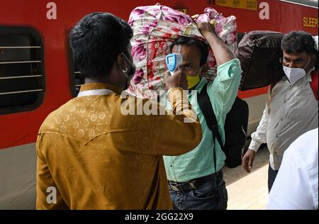 Mumbai, Indien. August 2021. Ein Mitarbeiter des Gesundheitswesens überprüft die Temperatur eines Mannes am Dadar Terminus.Passagiere, die mit dem Außenbahnhof ankommen, müssen sich einer Temperaturprüfung und in einigen Fällen einem RT-PCR-Test unterziehen, bevor sie zu ihrem jeweiligen Ziel fahren dürfen. Kredit: SOPA Images Limited/Alamy Live Nachrichten Stockfoto