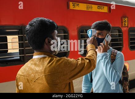 Mumbai, Indien. August 2021. Ein Mitarbeiter des Gesundheitswesens überprüft die Temperatur eines Mannes am Dadar Terminus.Passagiere, die mit dem Außenbahnhof ankommen, müssen sich einer Temperaturprüfung und in einigen Fällen einem RT-PCR-Test unterziehen, bevor sie zu ihrem jeweiligen Ziel fahren dürfen. (Foto von Ashish Vaishnav/SOPA Images/Sipa USA) Quelle: SIPA USA/Alamy Live News Stockfoto