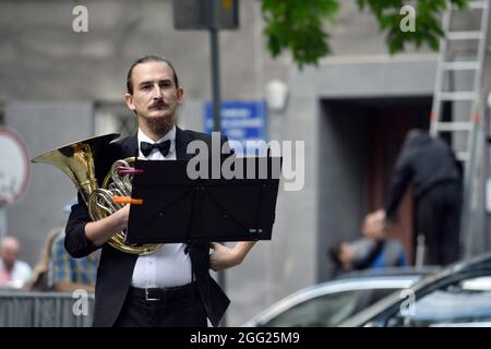 LVIV, UKRAINE - 26. AUGUST 2021 - EIN Musiker hält das französische Horn während der Eröffnung der allegorischen Skulptur des Komponisten, Pianisten, Dirigenten und Stockfoto