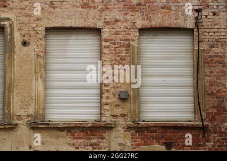 Geschlossener Rollladen auf dem Fenster in der Ziegelfassade Stockfoto