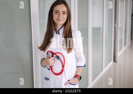Portrait junge Ärztin mit einem Stethoskop in den Händen. Helle Klinik Stockfoto