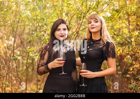 Zwei Frauen mit Gläsern Kelch mit Weißwein während eines eleganten Banketts. Herbstparty im Freien Stockfoto