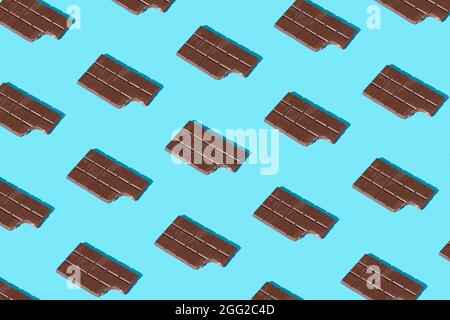 Draufsicht auf gebissene Milchschokolade mit blauem Hintergrund. Minimalkonzept von süßen Lebensmitteln. Flach liegend. Stockfoto