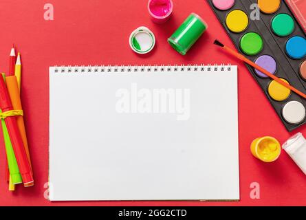 Schule liefert flach legen. Schreibwaren auf rotem Hintergrund, Draufsicht. Bildung, Back to School, Kinder Kreativität Konzept Stockfoto