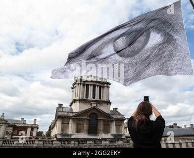 London UK 28 August 2021 Jessica Ella aus London fotografiert die riesige Flagge, künstlerische Installation. Von Dan Achers We are Watching, Teil des Greenwich und. Docklands International Festival 2021.Paul Quezada-Neiman/Alamy Live News Stockfoto
