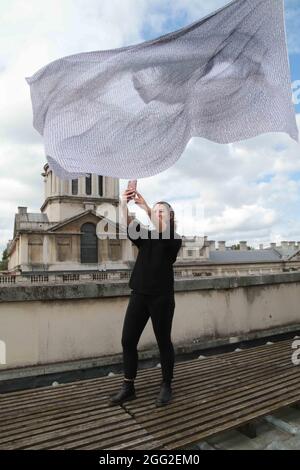 London UK 28 August 2021 Jessica Ella aus London nimmt ein Selfie mit der riesigen Flagge ,künstlerische Installation. Von Dan Achers We are watching, Teil der Greenwich and. Docklands International Festival 2021.Paul Quezada-Neiman/Alamy Live News Stockfoto