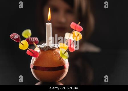 Ein kleines Mädchen schaut sich den Orange Christingle an, den sie gemacht hat Stockfoto