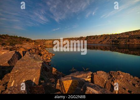 Ein sehr kleiner schöner See umgeben von großen Haufen Steinmüll aus harter Arbeit in der Mine Stockfoto