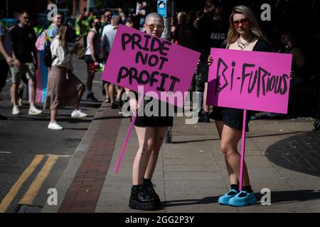 Manchester, Großbritannien. August 2021. Zwei Demonstranten mit Plakaten warten auf den Beginn des Pride-Protests. Hunderte von Menschen marschieren durch die Stadt, um gegen Manchester Pride Ltd zu protestieren.die Demonstranten fordern eine verbesserte Finanzierung für die LGBTQIA-Wohltätigkeitsorganisationen und Gemeindegruppen von Manchester. Kredit: Andy Barton/Alamy Live Nachrichten Stockfoto