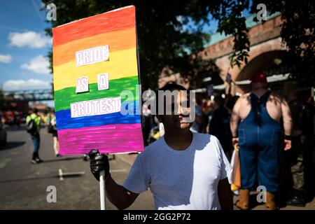 Manchester, Großbritannien. August 2021. Ein Protestler mit Plakat erwartet den Beginn des Pride-Protestes. Hunderte von Menschen marschieren durch die Stadt, um gegen Manchester Pride Ltd zu protestieren.die Demonstranten fordern eine verbesserte Finanzierung für die LGBTQIA-Wohltätigkeitsorganisationen und Gemeindegruppen von Manchester. Kredit: Andy Barton/Alamy Live Nachrichten Stockfoto