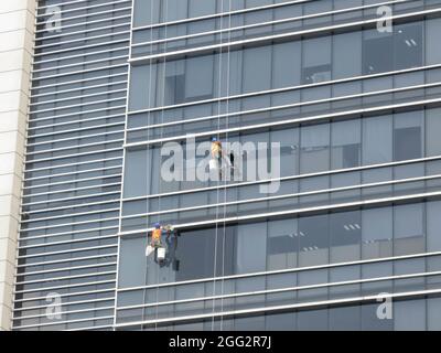 Ho Chi Minh, Vietnam - 28. Februar 2017: 2 Arbeiter reinigen das Außenglas eines Hochhauses Stockfoto