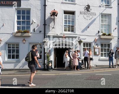 Lake Windermere .Cumbria . 28. August 2021 UK Wetter .Touristen, die das Wochenend-Wetter der Bankfeiertage für Bootsausflüge, Essen im Freien und Heiraten optimal ausgenießen Mr & Mrs Andrew & Levie Lee, die in der Kneipe Schlange stehen. Kredit: Gordon Shoosmith/Alamy Live Nachrichten Stockfoto