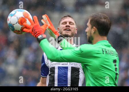 Bielefeld, Deutschland. August 2021. Fußball: Bundesliga, Arminia Bielefeld - Eintracht Frankfurt, Matchday 3 in der Schüco Arena. Bielefelds Fabian Klos (l) kämpft mit dem Frankfurter Torwart Kevin Trapp (r) um den Ball. Kredit: Friso Gentsch/dpa - WICHTIGER HINWEIS: Gemäß den Bestimmungen der DFL Deutsche Fußball Liga und/oder des DFB Deutscher Fußball-Bund ist es untersagt, im Stadion und/oder vom Spiel aufgenommene Fotos in Form von Sequenzbildern und/oder videoähnlichen Fotoserien zu verwenden oder zu verwenden./dpa/Alamy Live News Stockfoto