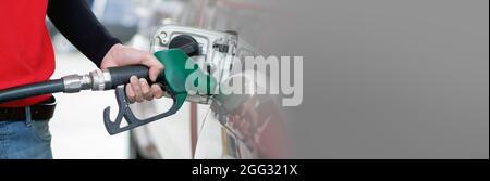 Tankstellenmitarbeiter in roter Uniform füllen Bronze Pickup LKW-Tank. Nahaufnahme Hand hält grüne Gaspumpe Düse. Stockfoto