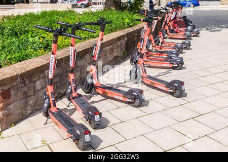 BRISTOL, Großbritannien - 19. AUGUST 2021: VOI. Elektro-Scooter auf einer Straße in Bristol während des Tages. Im Hintergrund ist eine Person zu sehen. Stockfoto