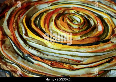 Gemüsekuchen mexikanische Sonne. Runde, offene Torte aus Zucchini, Auberginen und Karotten. Nahaufnahme von oben. Gesunde pflanzliche Lebensmittel. Vegetarismus. Spirale Stockfoto