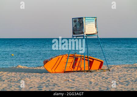 Hel, Polen - 08.01.2021: Rettungsschwimmer stehen mit orangefarbenem Boot darunter an einem Strand im goldenen Stundenlicht. Leerer Strand an der Ostseeküste früh Stockfoto