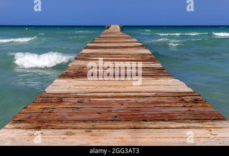 PLAYA DE MURO, SPANIEN - 25. JULI: Das plätschernde Meer ist am 25. Juli 2021 von einem Steg in Playa de Muro, Spanien, zu sehen. Stockfoto