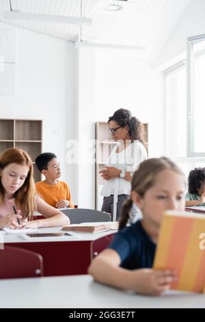 afroamerikanische Lehrerin im Gespräch mit einem asiatischen Schuljungen während des Unterrichts Stockfoto