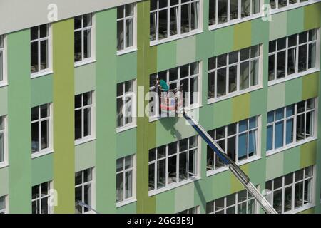 Nischni Nowgorod, Russland, Gagarin Avenue 101 b, Schule Nr. 34. 08.26.2021. Eine Frau, Angestellte einer Reinigungsfirma, wäscht die Fenster des Gebäudes Stockfoto