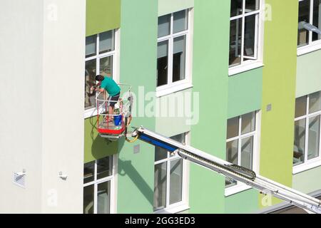 Nischni Nowgorod, Russland, Gagarin Avenue 101 b, Schule Nr. 34. 08.26.2021. Eine Frau, Angestellte einer Reinigungsfirma, wäscht die Fenster des Gebäudes Stockfoto