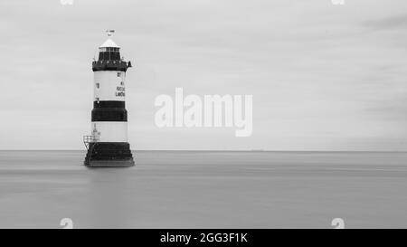 DER LEUCHTTURM TRWYN DU BEI PENMON AUF DER INSEL ANGLSEY, NORDWALES, WURDE BEI LANGER BELICHTUNG AN EINEM RUHIGEN TAG MIT DEM MEER BEWEGUNGSLOS UND GLATT GEDREHT Stockfoto