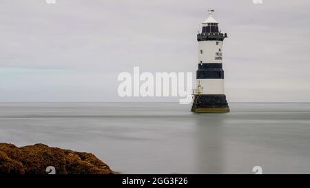 DER LEUCHTTURM TRWYN DU BEI PENMON AUF DER INSEL ANGLSEY, NORDWALES, WURDE BEI LANGER BELICHTUNG AN EINEM RUHIGEN TAG MIT DEM MEER MOTIONLESSAND GLATT GEDREHT Stockfoto