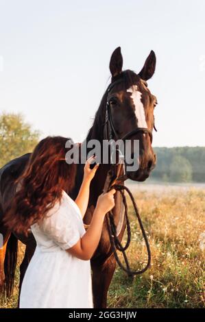 Vertikale Aufnahme mit flachem Fokus einer Frau, die ein Pferd streicheln Stockfoto