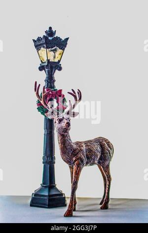 Hirsch-Figur steht an Retro-Weihnachts-Lampost mit Kranz vor weißem Hintergrund - Platz für Kopie. Stockfoto