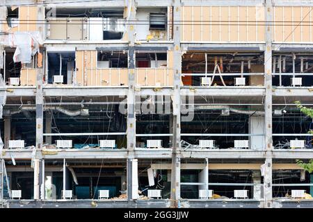 Fragment der zerstörten mehrstöckigen Fassade eines modernen Geschäftsgebäudes mit durchscheinenden Öffnungen und Betondecken. Stockfoto