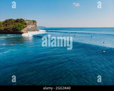 Lange Wellenreiten im blauen Ozean und Klippe im Hintergrund. Luftaufnahme der tropischen Insel mit Wellen Stockfoto