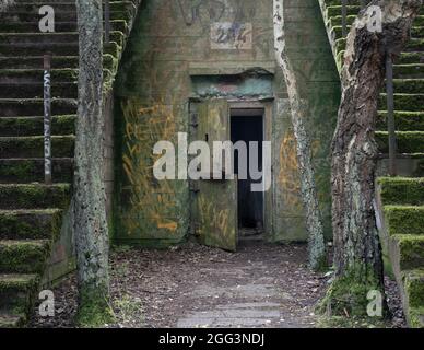 Offene Stahltür eines verlassenen Militärbunkers aus Beton in Hel, Polen. Der zweite Weltkrieg und die Artillerie-Festung aus dem Kalten Krieg, die in der Mitte auseinander fällt Stockfoto