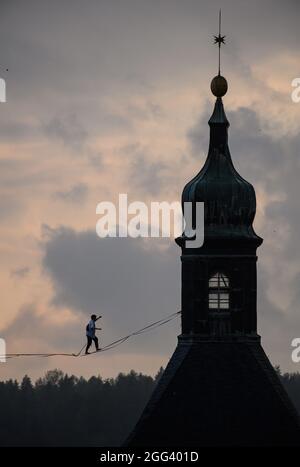 Hohnstein, Deutschland. August 2021. Ruben langer, Slackline-Weltrekordler, balanciert am Seil zwischen Schloss und Stadtkirche der Stadt in der Sächsischen Schweiz beim Highline - und Familienfest. Die Slackline erstreckt sich über mehr als 100 Meter über den Marktplatz und ist 30 Meter lang. Rund um die Burg Hohnstein sind insgesamt 4 Seile installiert, die längste ist 360 Meter lang über das Polenztal. Quelle: Robert Michael/dpa-Zentralbild/dpa/Alamy Live News Stockfoto