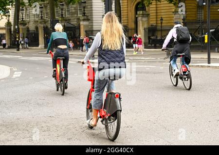 London, England - 2021. August: Menschen, die auf einer Straße mit Elektrofahrrädern fahren. Die Fahrräder können im Lime Bike-Fahrradverleihsystem ausgeliehen werden Stockfoto