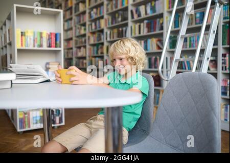 Fröhlicher Junge, der das Gadget in seinen Händen anstarrt Stockfoto