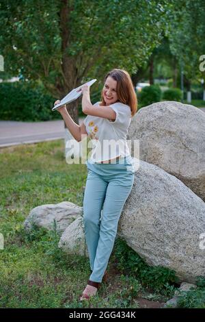 Ein verärgertes Mädchen steht mit einem Laptop in der Natur Stockfoto
