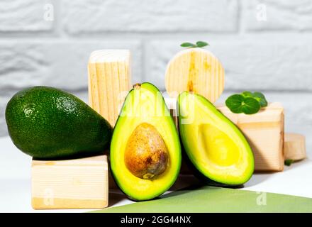Hälften von reifen Avocado und Micro Green auf Holzbrett serviert auf dem Tisch, weißer Hintergrund, gesunde ölige Lebensmittel, Keto-Diät, Nahaufnahme. Stockfoto
