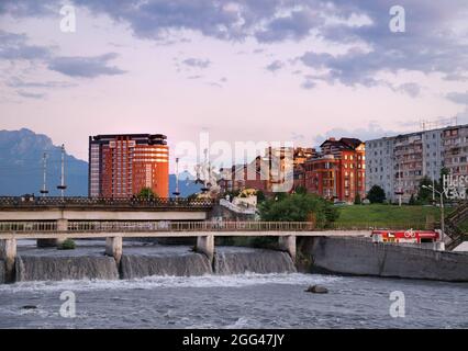 Sommer Sonnenuntergang Blick auf Vladikavkaz Innenstadt Gebäude mit Stolovaya Berg im Hintergrund und Stromschnellen und Brücken ov Fluss Terek im Vordergrund. Russland Stockfoto