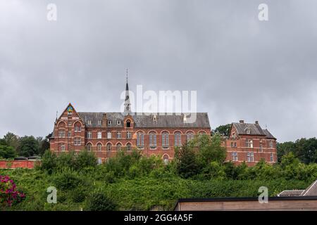 Dinant, Wallonien, Belgien - 8. August 2021: Altes Kapuzinerkloster aus rotem Stein, heute Hotel, Museum und Verwaltungsgebäude unter Wolkenlandschaft Stockfoto