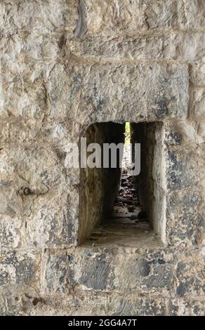 Dinant, Wallonien, Belgien - 8. August 2021: Festung Zitadelle. Nahaufnahme eines Schießlochs in einer sehr dicken grauen Steinmauer. Stockfoto