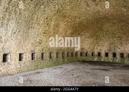 Dinant, Wallonien, Belgien - 8. August 2021: Festung Zitadelle. Beigefarbener Ziegelstein untergezacktem Lagerplatz. Leer mit dunklen Nischen. Stockfoto