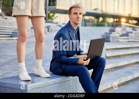 Geschäftsmann in Anzug mit Laptop und Frau in der Nähe des Bürozentrums. Stockfoto