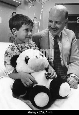 Austin Texas USA, um 1993: Kinderarzt lässt junge Patienten im Kinderkrankenhaus Stethoskop verwenden, um dem Herzen des Teddybären zuzuhören. HERR ©Bob Daemmrich Stockfoto