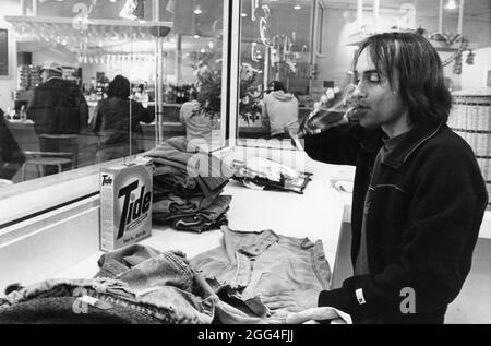 Austin Texas USA, um 1983: Der Mäzen des Unternehmens „Barwash“ macht seine Wäsche, während er ein Glas Bier genießt. ©Bob Daemmrich Stockfoto