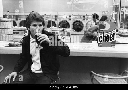 Austin Texas USA, um 1983: Der Mäzen des Unternehmens „Barwash“ macht seine Wäsche, während er ein Glas Bier genießt. ©Bob Daemmrich Stockfoto