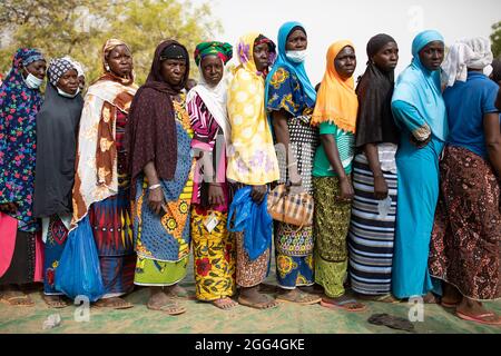 An einem Verteilungsort des IDP-Lagers in Nouna, Burkina Faso, Westafrika, stehen Frauen an, um Nahrungsmittelhilfe zu erhalten. Stockfoto