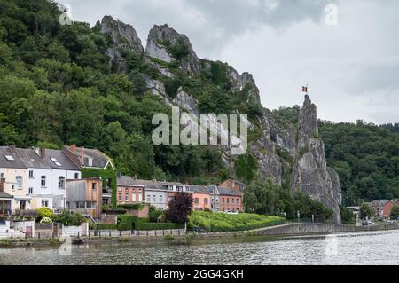 Dinant, Wallonien, Belgien - 8. August 2021: Der berühmte Le Rocher Bayard und seine nachgelagerte Umgebung mit allgemeinen Häusern in verschiedenen Farben, grün Stockfoto