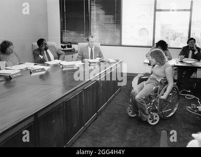 Austin Texas USA, 1987: Frau im Rollstuhl spricht mit Beamten, während Mitglieder der Behindertengemeinschaft bei der Sitzung des Stadtautos mit voller Kraft für einen besseren Busverkehr eintreten. ©Bob Daemmrich Stockfoto