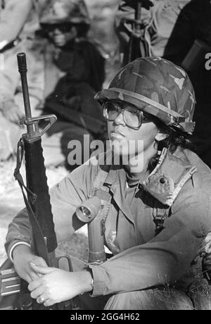 Fort Hood Texas USA, 1990: Weibliche US-Armee-Soldatin in wüstenfarbener Tarnuniform und mit Waffe und Ausrüstung bereitet sich darauf vor, auf dem Weg zum Nahost-Konflikt an Bord eines Flugzeugs zu gehen. ©Bob Daemmrich Stockfoto